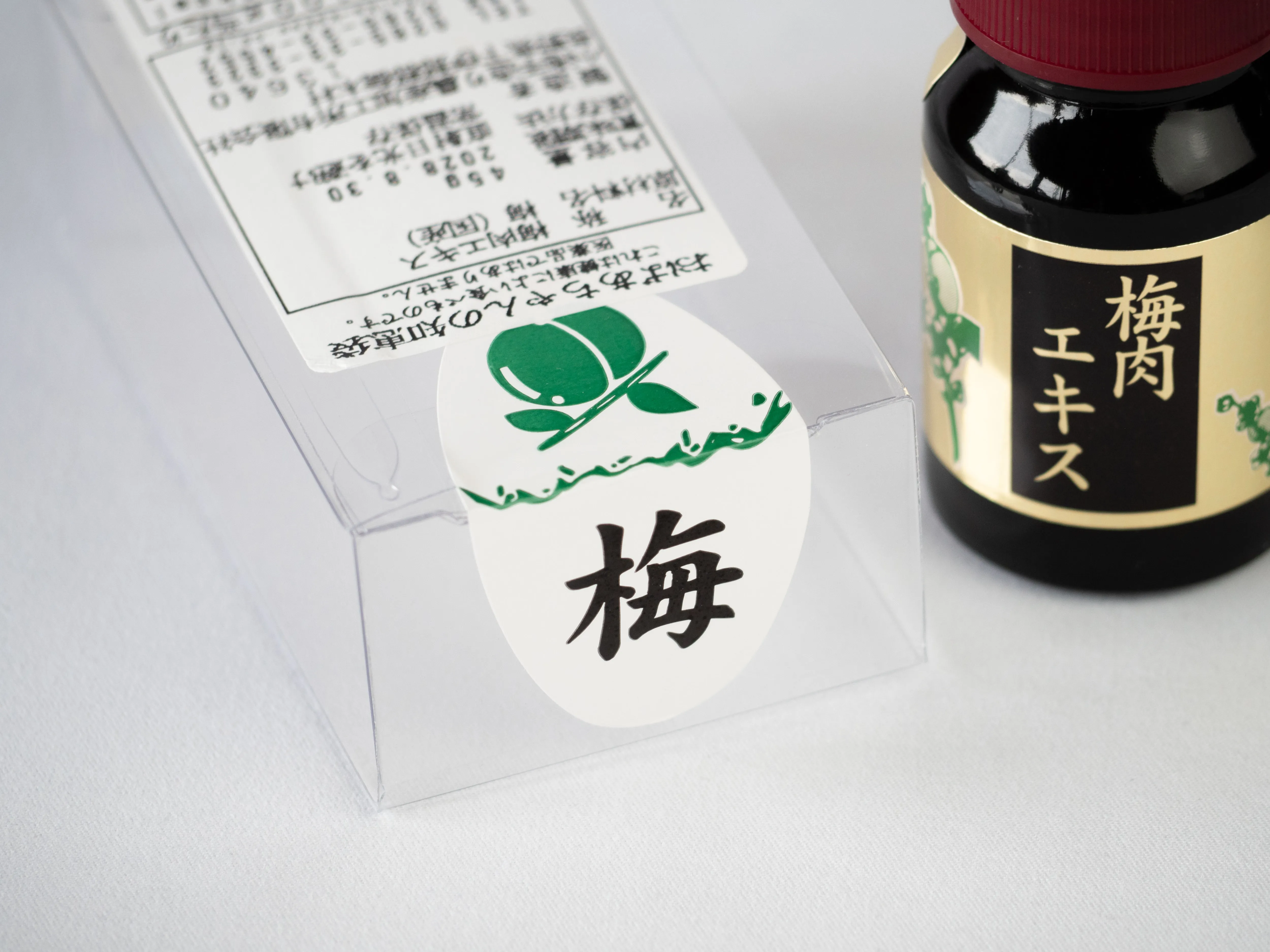 透明な外箱に貼った梅の文字のシールと梅肉エキスの小瓶