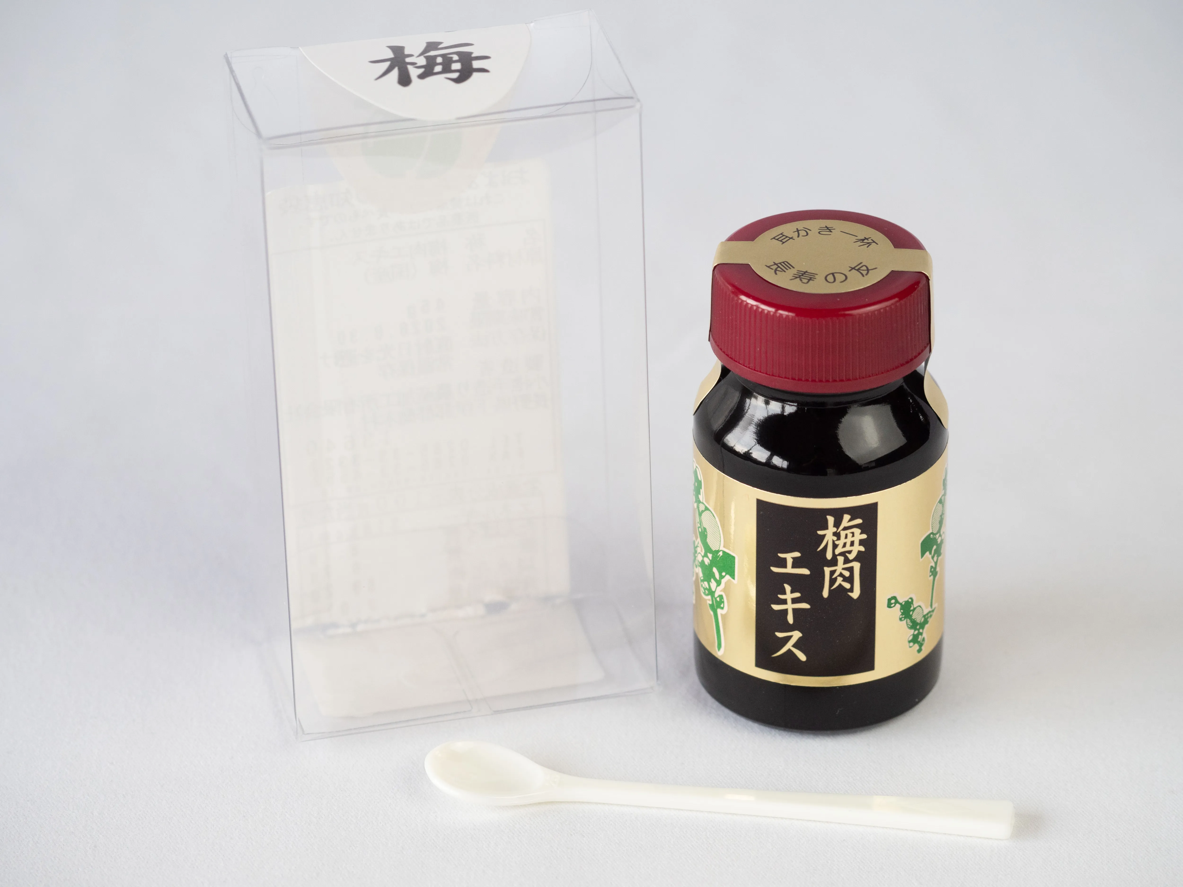 透明な外箱の梅シールと、金消しホイルのラベルを貼った梅肉エキスの小瓶