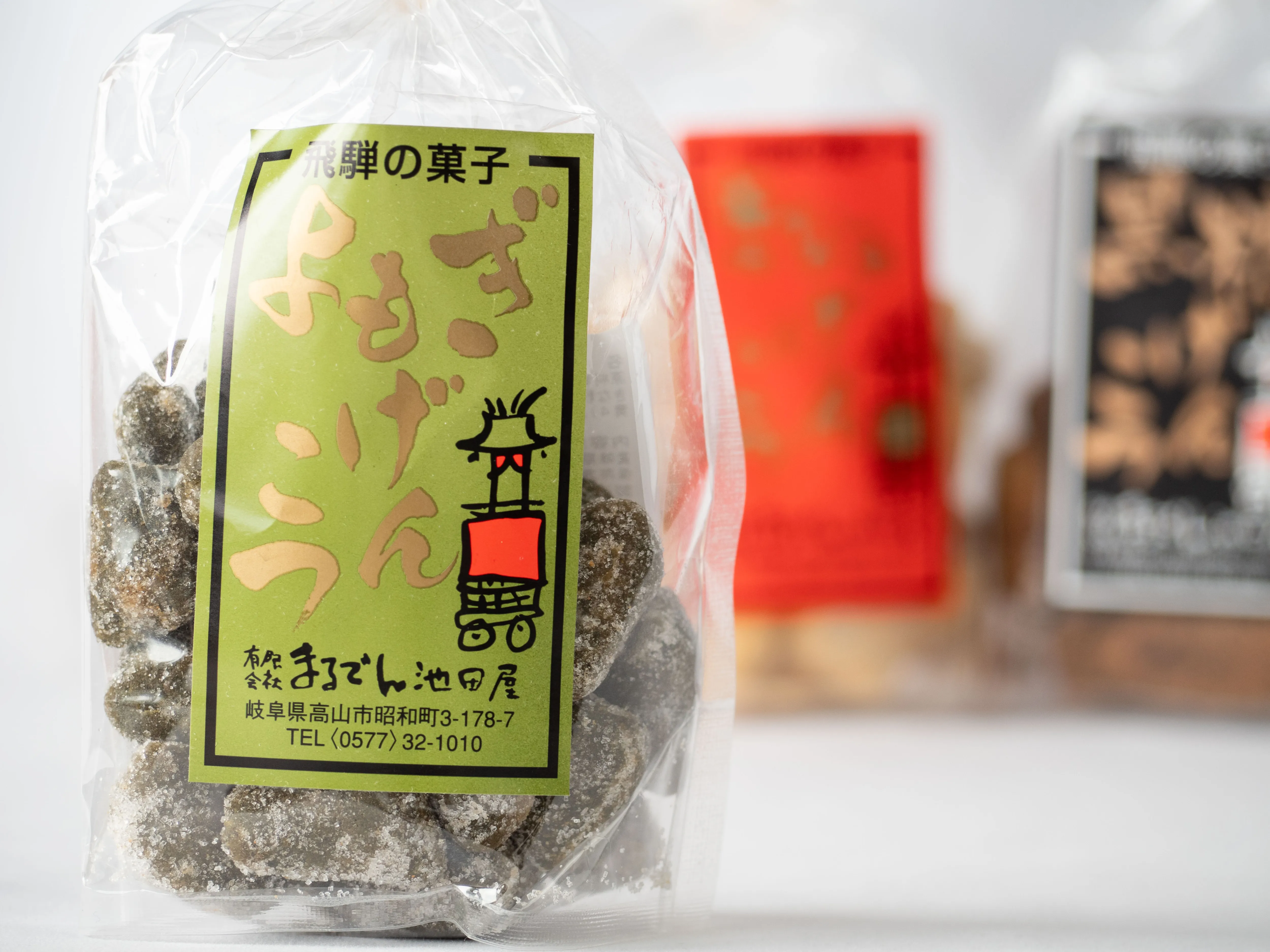 よもぎげんこつの緑色ラベルの近景と、背景に写る赤・黒のシリーズ商品